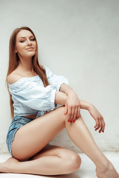 Beautiful woman with brown hairs poses near wall — Stock Photo, Image