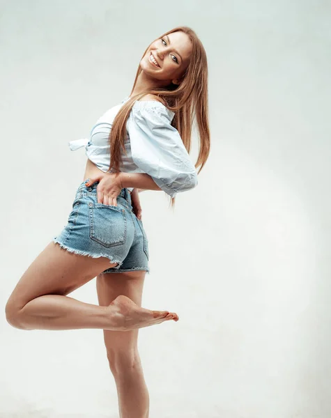 Veselá dívka pózuje se zvednutou nohou v bílém pozadí — Stock fotografie