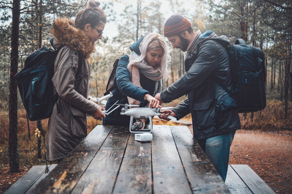 Lovely autumn forest and students they tuning quadcopter