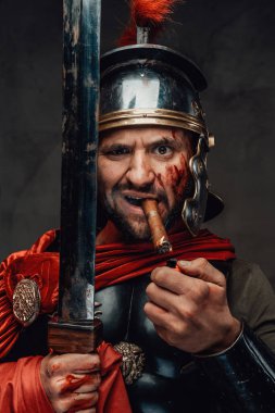 Esmer arka planda purosu ve kılıcı olan ciddi bir Romalı asker.