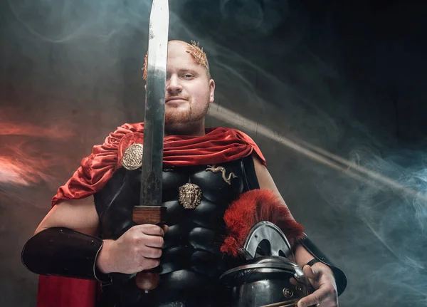 Kale legionair met zwaard poseert in smokey achtergrond met verlichting — Stockfoto