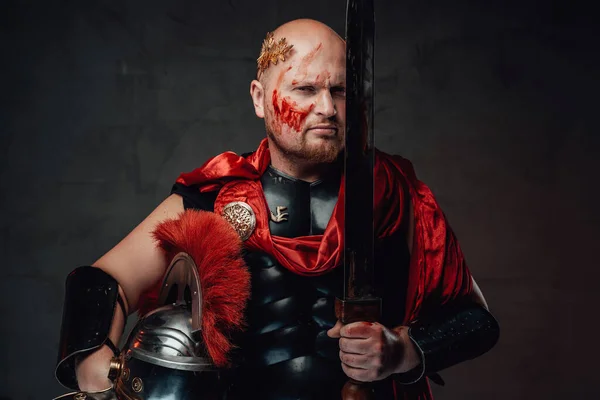 Guardião romano posa com espada perto de seu rosto em fundo escuro — Fotografia de Stock