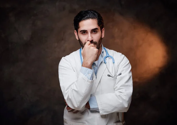 Pensive physician in white labcoat pose in dark background — Stock Photo, Image