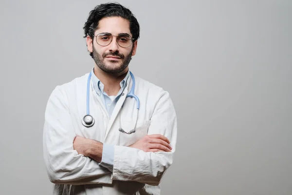 Médico posa con brazos cruzados en fondo blanco —  Fotos de Stock