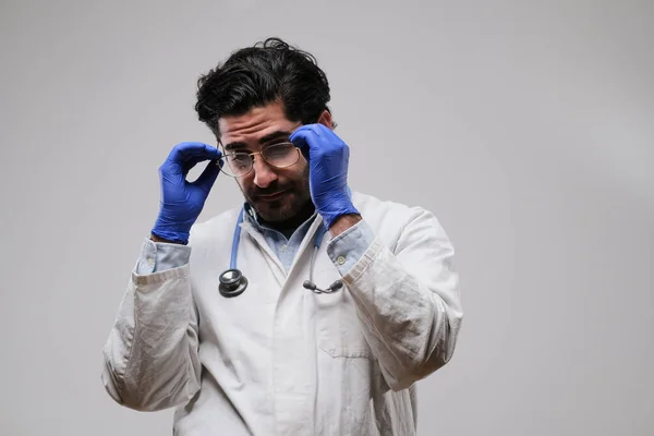 Médecin en manteau de laboratoire portant ses lunettes en fond blanc — Photo
