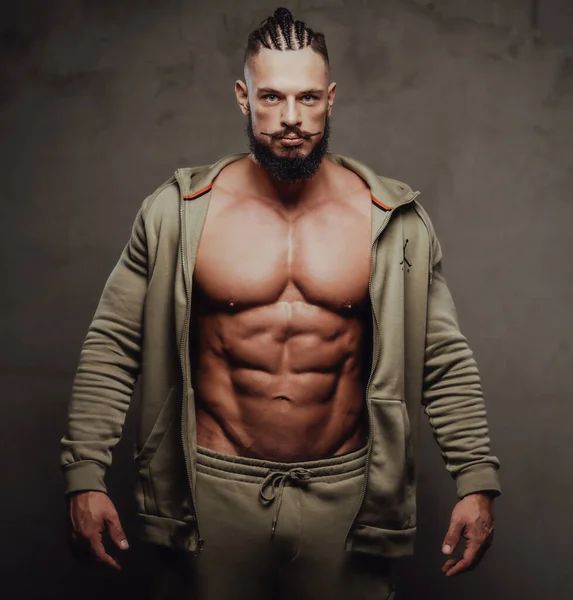 Hombre fuerte y deportivo con abdominales posa en ropa deportiva gris — Foto de Stock