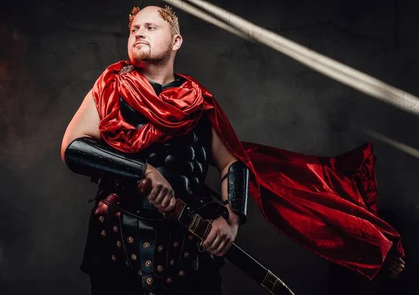 Волохатий римський воїн позує з червоним мисом на темному тлі — стокове фото