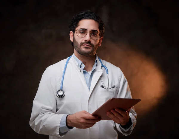 Magabiztos és képzett orvos sötét hátterű tablettával — Stock Fotó