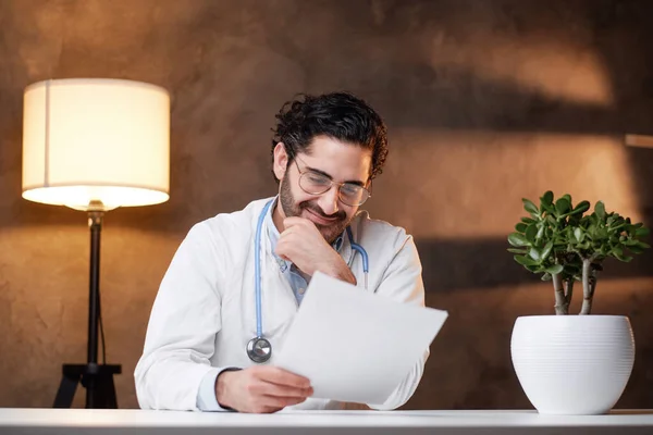 Geconcentreerde arts typen met behulp van zijn laptop zitten aan tafel — Stockfoto