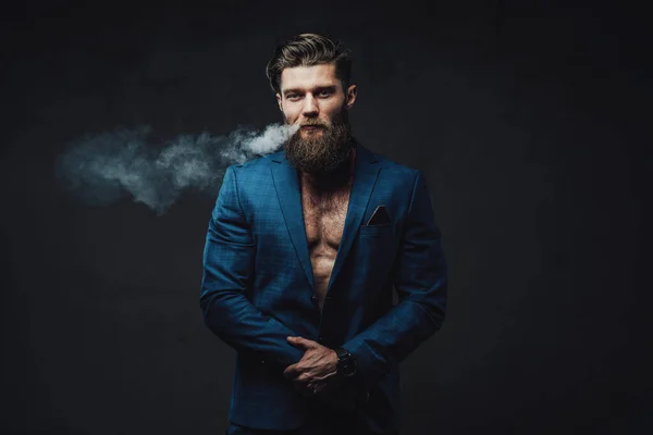 Елегантність стилізований чоловік з бородою курить на темному фоні — стокове фото