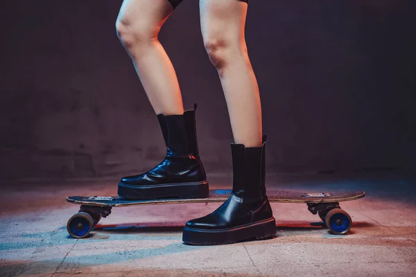 Женские ноги на скейтборде на темном фоне с огнями — стоковое фото