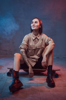 Şık giyinmiş, kısa saçlı, kaykaylı neşeli bir kadın.