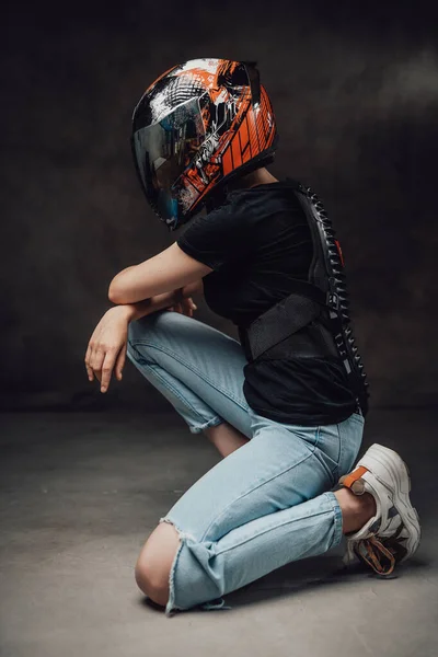 Vrouwelijke motorrijder met sportieve helm in shirt poseert in donkere achtergrond — Stockfoto