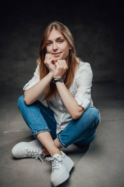 Uzun saçlı, siyah arka planda günlük kıyafetler giyen güzel bir kız.