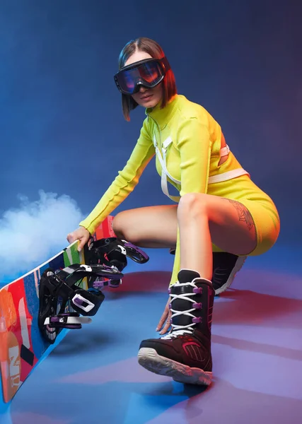 Linda chica con gafas de esquí y snowboard posa en el estudio — Foto de Stock