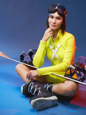 Snowboard 'lu şirin kız mavi arka planda poz veriyor.