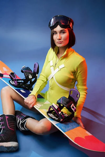 Menina bonita em sportswear amarelo com snowboard e óculos — Fotografia de Stock