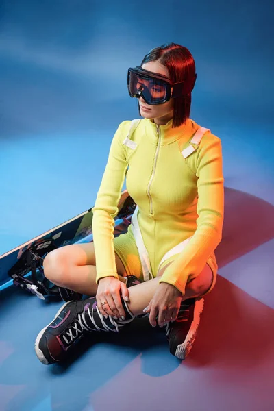 Linda chica en ropa deportiva con snowboard en fondo de color — Foto de Stock