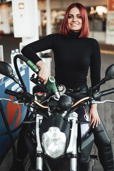 Mulher ruiva bonita enchendo sua moto em serviço — Fotografia de Stock