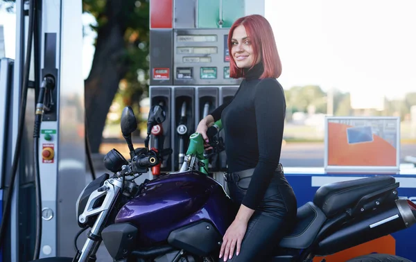 Piękna młoda dziewczyna siedzi na rowerze na stacji benzynowej — Zdjęcie stockowe
