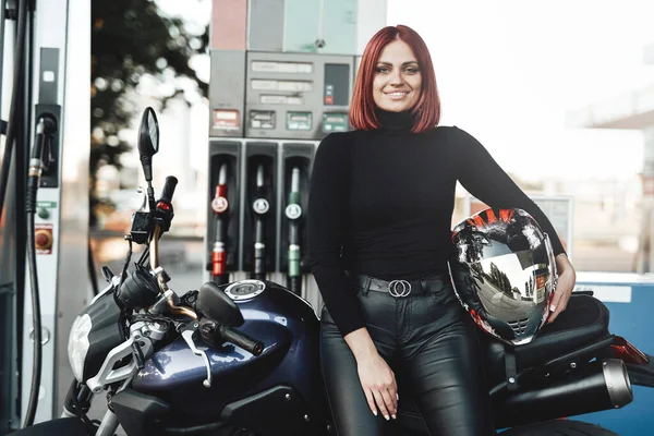 Uśmiechnięta ruda kobieta ze swoim rowerem na stacji benzynowej — Zdjęcie stockowe