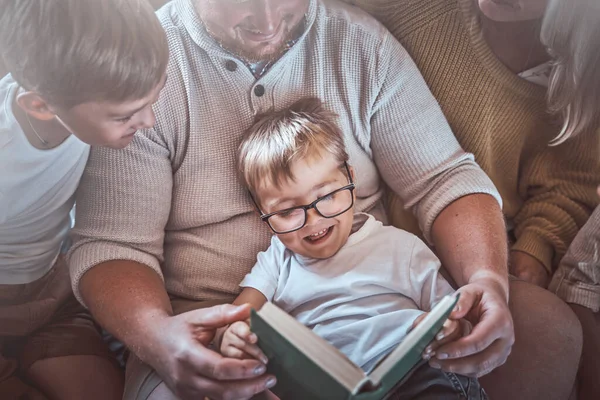Família feliz lendo um livro juntos na sala de estar quente — Fotografia de Stock
