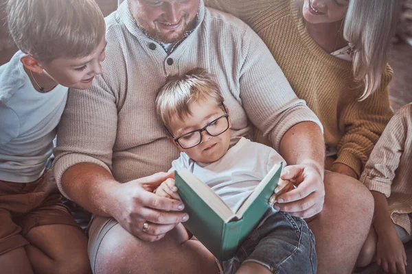 Família feliz lendo um livro juntos na sala de estar quente — Fotografia de Stock