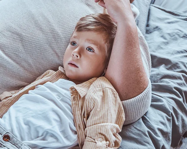 Father and son lying on a bed in living room — Stock Photo, Image