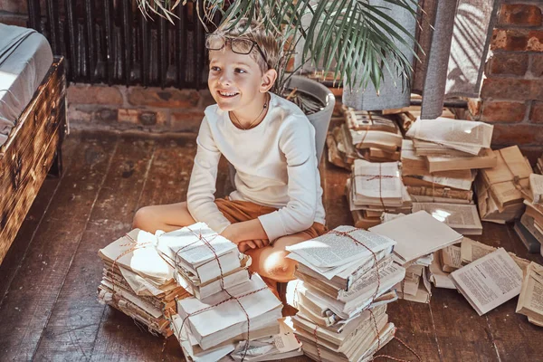 Joyful garoto sentado no chão no apartamento em torno de livros — Fotografia de Stock