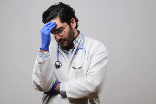 Médecin fatigué en uniforme blanc avec lunettes et gants en caoutchouc bleu — Photo