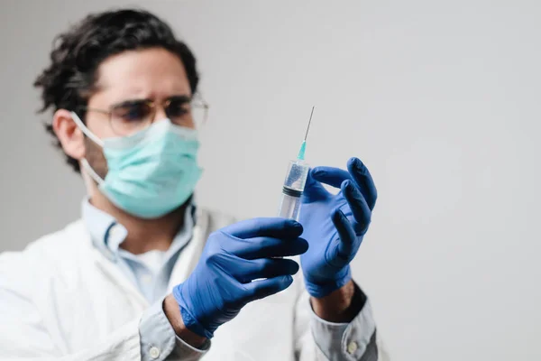 Focused doctor with mask prepares injection in lab