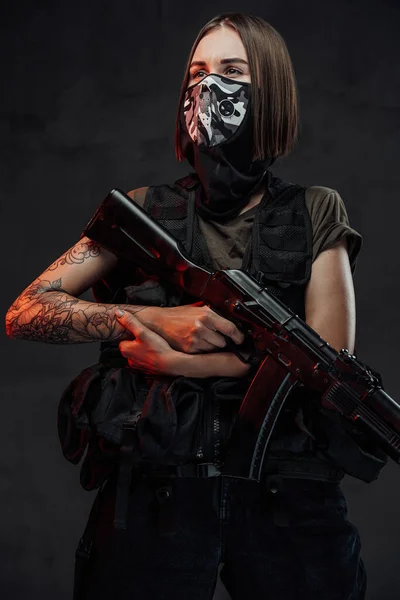 Weared with mask female mercenary holding rifle