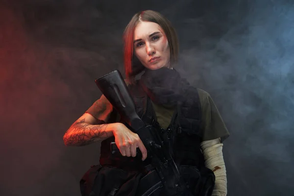 Ernstige martial woman met geweer poses in smokey donkere achtergrond — Stockfoto