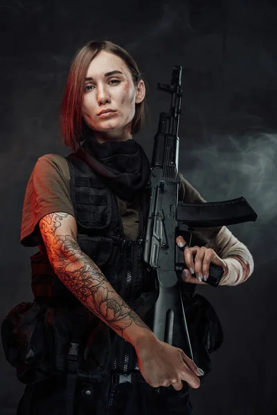 Schöne Soldatin mit Gewehr auf der Schulter im rauchigen Hintergrund — Stockfoto