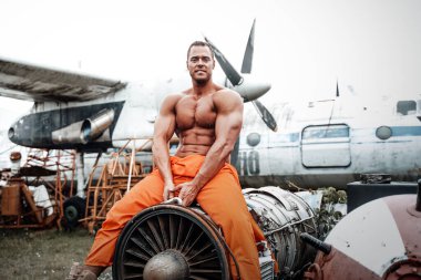 Gündüz vakti uçağın motorunda oturan pozitif vücutgeliştirici.