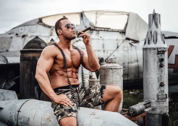 Posando sobre torpedo shirtless militar cara no aeroporto abandonado — Fotografia de Stock