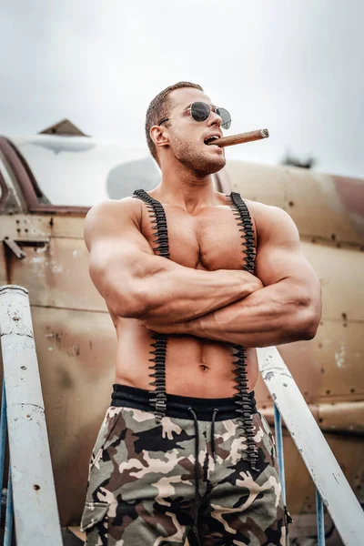 Muskularny żołnierz topless w okularach przeciwsłonecznych palący cygaro — Zdjęcie stockowe