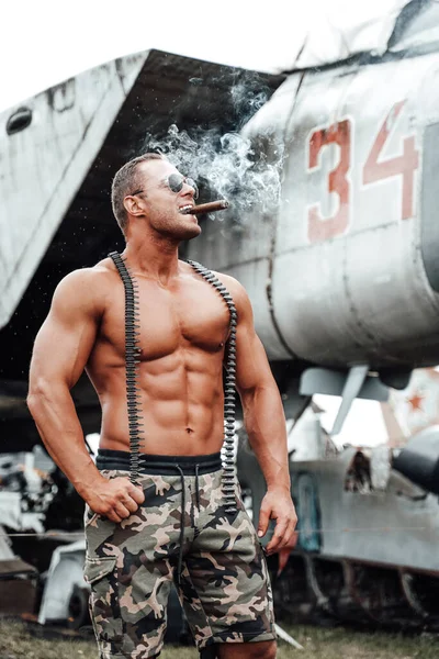 Stark militär kille med naken bål njuter av cigarr på flygplatsen — Stockfoto