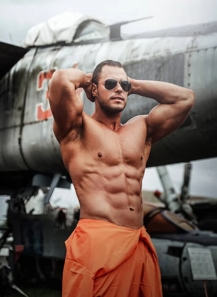 Naken muskelmekaniker poserar nära övergivna flygplan — Stockfoto