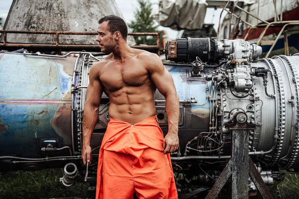 Mechanic macho with muscular build in orange clothing