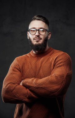 Siyah arka planda poz veren güçlü ve sakallı bir adam.