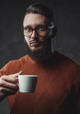 Elinde kahve fincanı tutan sakallı adam.