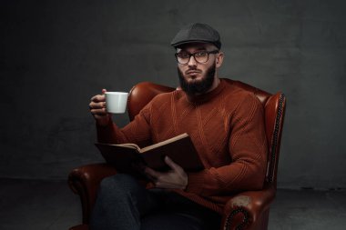 Süveter ve sandalyede kahve fincanı olan hippi şapkalı.