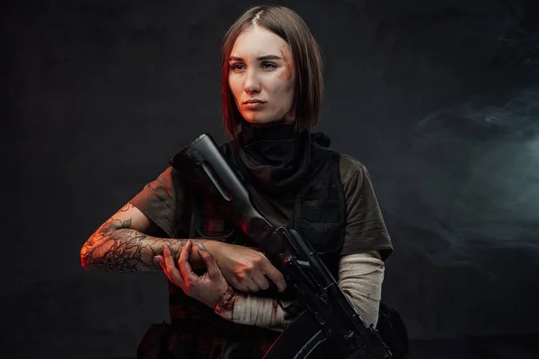 Női katona bekötözött karú puskával sötét háttérben — Stock Fotó