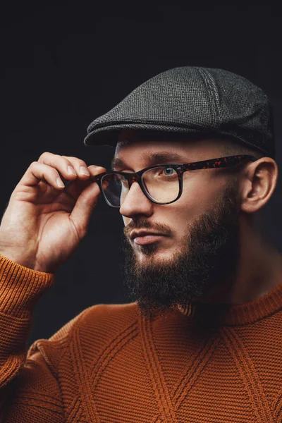 Sakallı ve şapkalı hippi koyu arkaplanda poz veriyor.