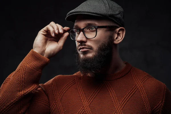 Hipster com barba e boné posa em fundo escuro — Fotografia de Stock