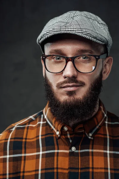 Karanlık arka planda kameraya bakan pozitif sakallı hippi.