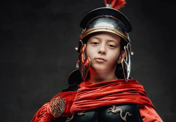 Dressed in legionary clothing cheerful boy in dark background — Stock Photo, Image