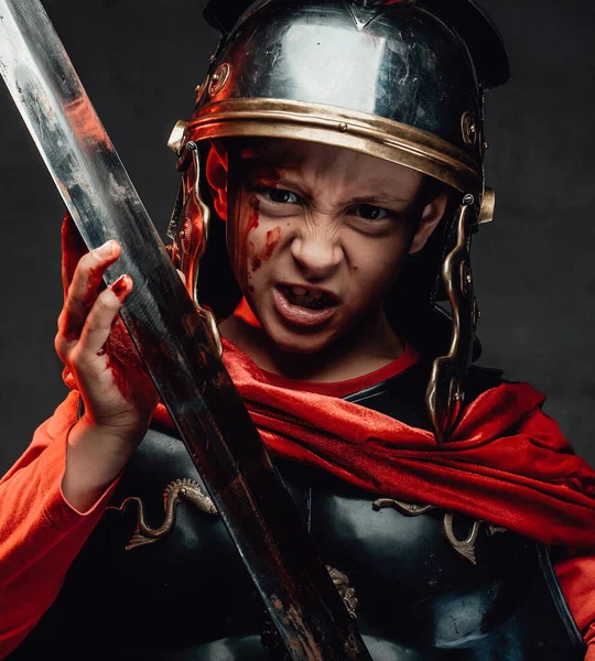 Loco niño romano guerrero sosteniendo una espada en el fondo oscuro — Foto de Stock
