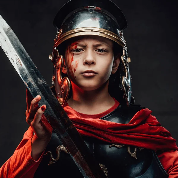 Niño romano serio y guerrero con espada en fondo oscuro — Foto de Stock